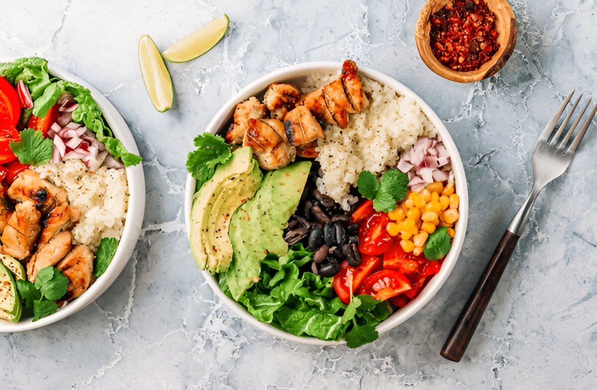 A colorful rice bowl topped with fresh vegetables, grilled chicken, and a drizzle of soy sauce, showcasing a healthy and delicious meal.