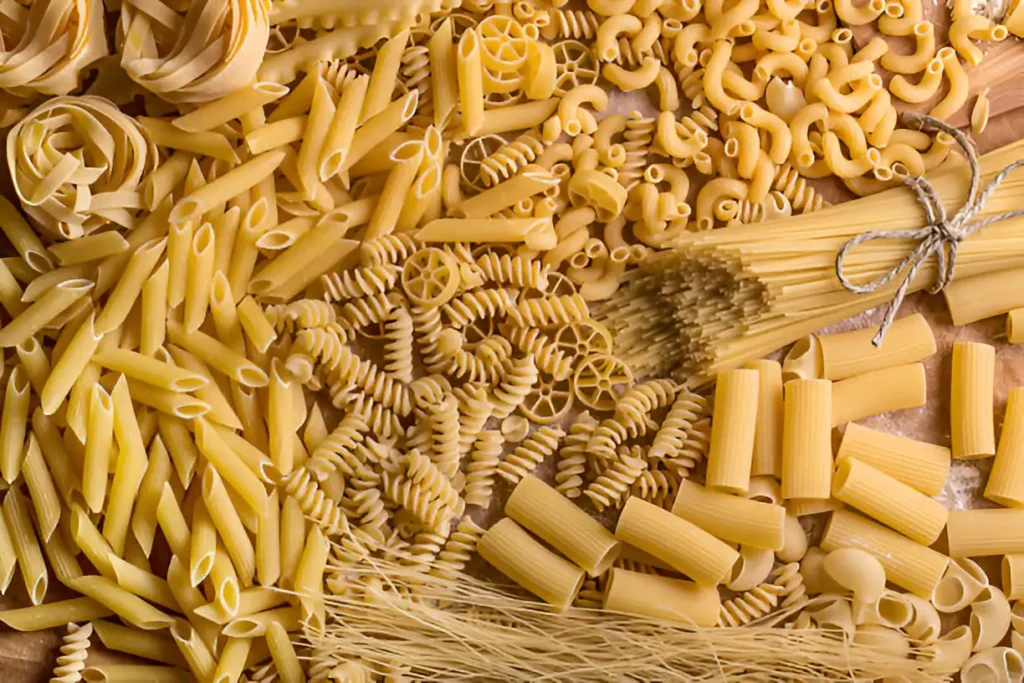 Various pasta types displayed in a vibrant, colorful spread, showcasing the diversity of pasta shapes and textures.